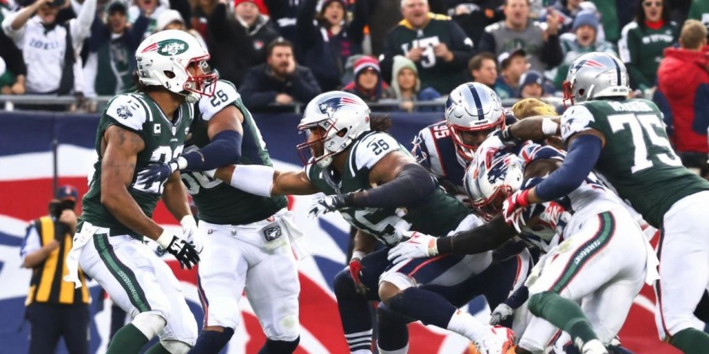 Jets and Patriots players on the football field during game.