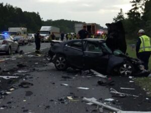 Damaged car and emergency responders at highway accident.