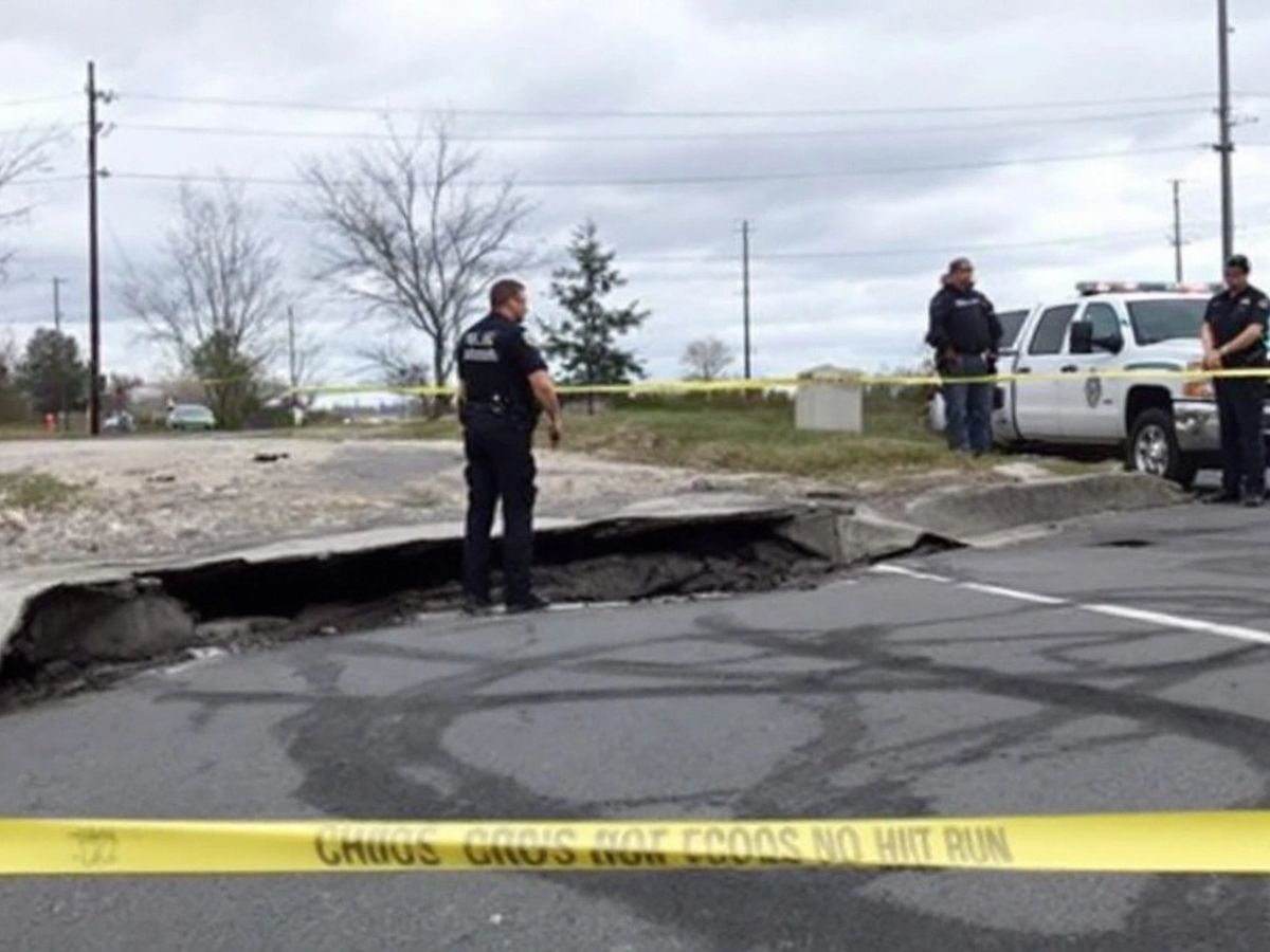 Police at a hit-and-run scene with damaged curb.