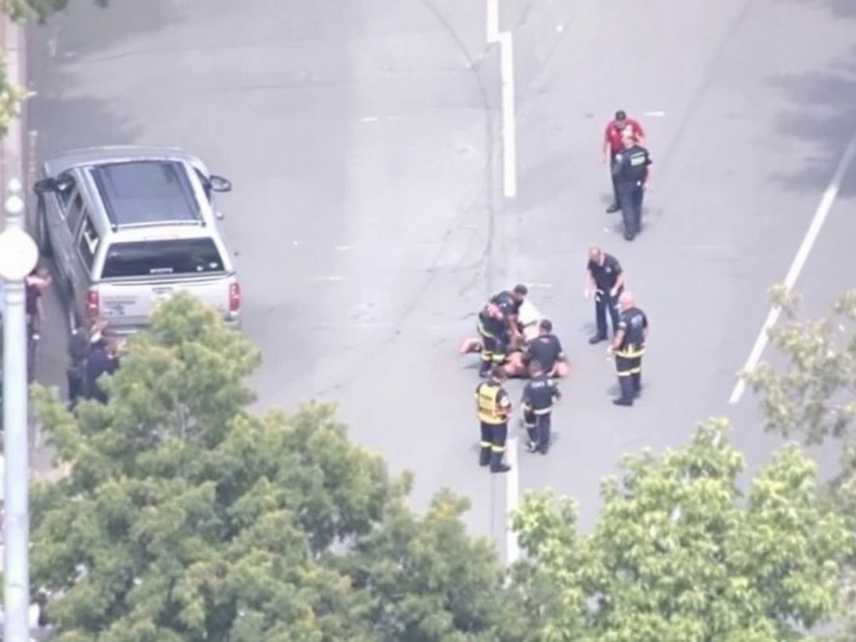 Emergency responders attending to an injured man on road.