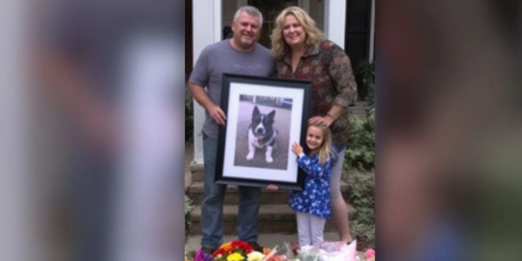 Grieving family holding dog photo outside their home.