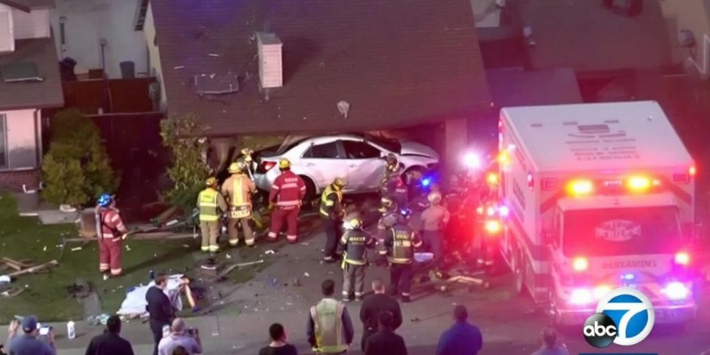 Car crash into a house with emergency responders nearby.